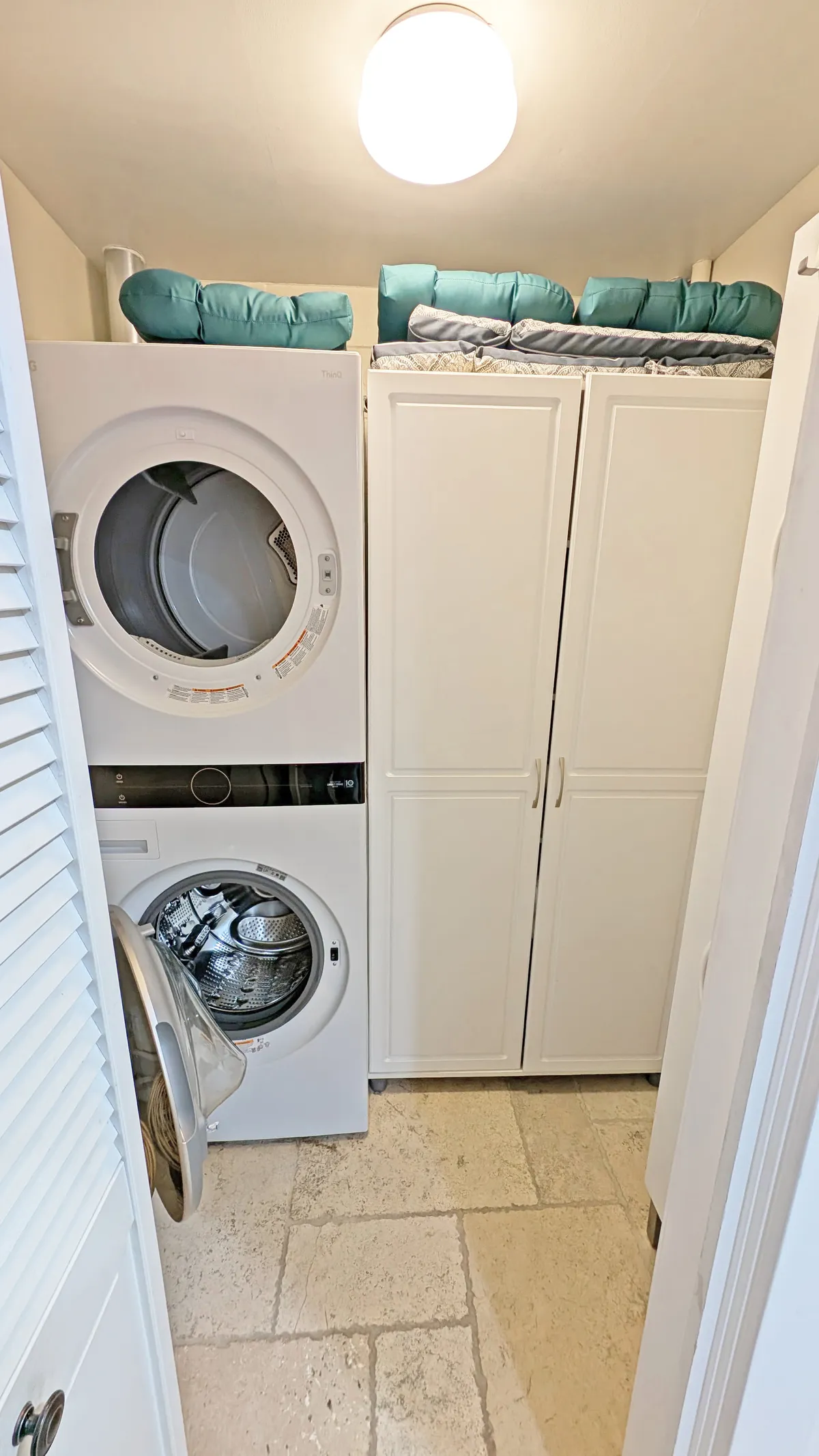 A tidy laundry area with a washer and dryer, ample storage cabinets, and blue cushions on a nearby bench. The space is neat and functional, suggesting ease of use after a day outdoors.