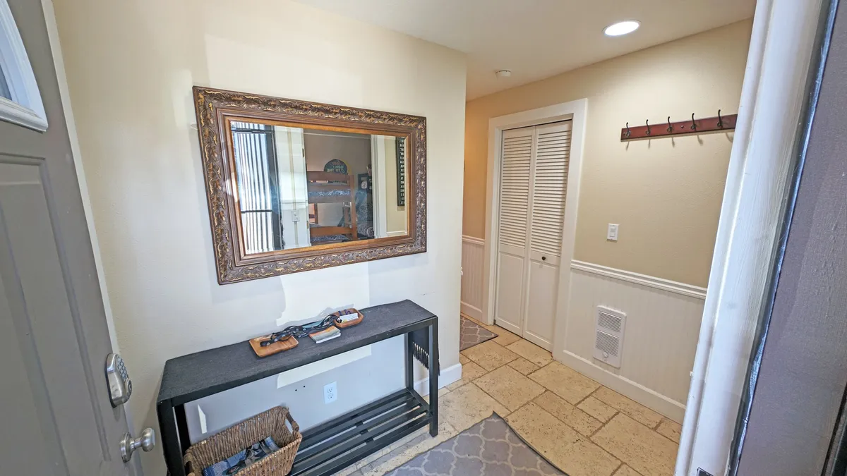 An inviting entryway featuring a mirror, console table, and wall hooks—ideal for stashing jackets, bags, or outdoor gear upon returning from adventures. The mood is welcoming and functional.